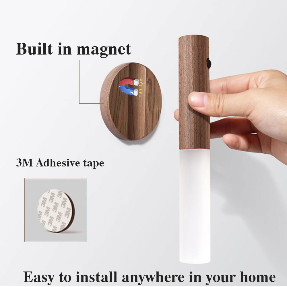 A hand holding the SmartNest™ rechargeable sensor light detached from its magnetic base, used as a portable handheld flashlight for night safety.